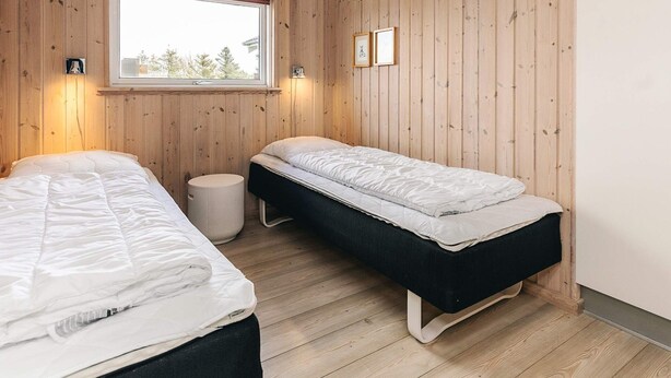 A room with two beds, a window, and wooden walls. - 5 Star Holiday Home in Lokken (Lokken)