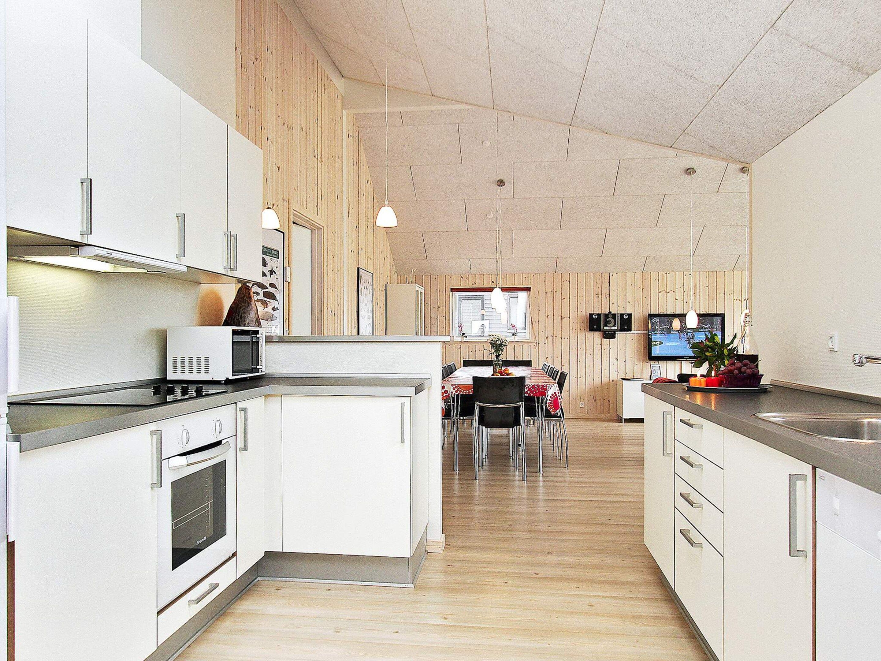 A modern kitchen with white cabinets, a microwave, and a dining area with a table and chairs.