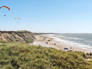 Paisaje costero con playa, acantilados y cielo despejado.