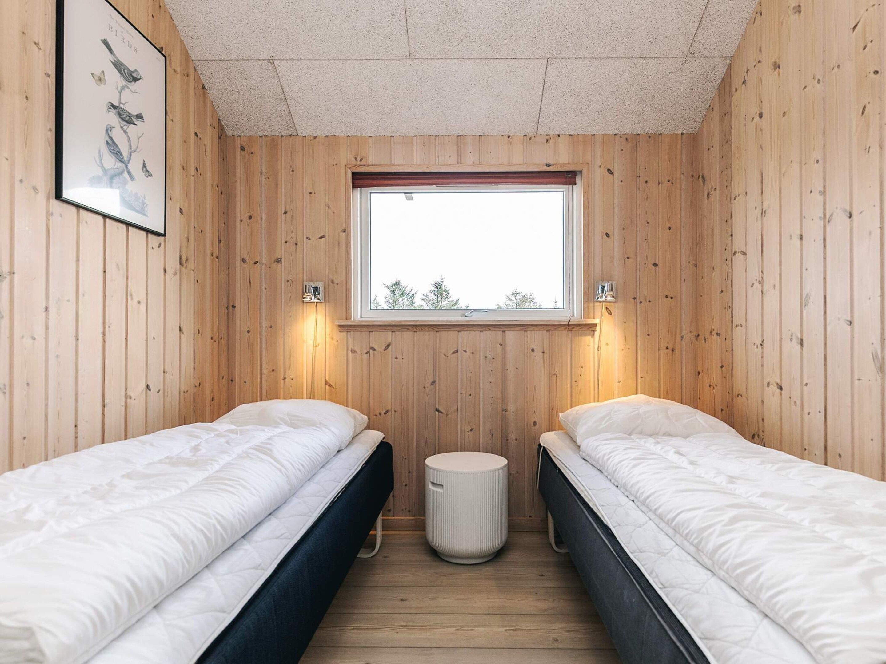 A room with two beds, a window, and a framed picture on the wall.