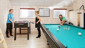 A pool table, foosball table, and wooden walls with windows. - 5 Star Holiday Home in Lokken (Lokken)