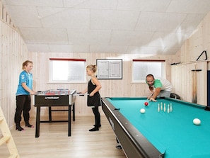 A pool table, foosball table, and wooden walls with windows. - 5 Star Holiday Home in Lokken (Lokken)