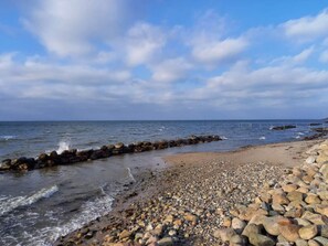 Une plage rocheuse où les vagues s’écrasent contre une digue.