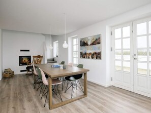A modern dining room with a wooden table, chairs, pendant lights, and artwork on the walls. - 7 Person Holiday Home in Bogense (Bogense)