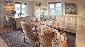 A cozy living room with a wooden dining table, two chairs, a sofa, and a patterned rug. - 7 Person Holiday Home in Averoy (Averoy)
