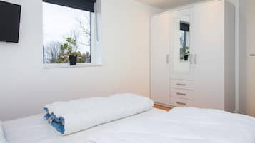 A bedroom with a bed, a wardrobe, a window with a view, and a potted plant.