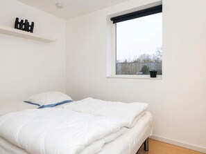 A bedroom with a bed, a window with a view of the outside, and a shelf with decorative items. - 4 Star Holiday Home in Odder (Odder)