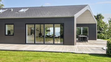 A modern house with a flat roof, large glass windows, and a deck.
