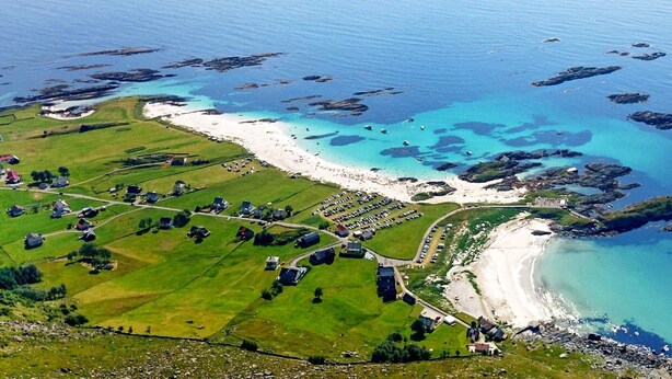 Oversigtsbillede af et kystområde med strand, grønne marker og spredte huse.