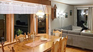 Et spiseområde med et træbord, stole, en hvidblonde bordløber og en hængende lampe.