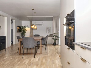 A modern kitchen with a dining area, wooden flooring, and pendant lighting. - 4 Star Holiday Home in Ebeltoft (Ebeltoft)