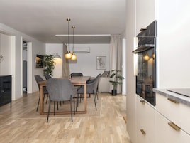 Cozinha moderna com área de refeições, piso de madeira e luminárias pendentes.