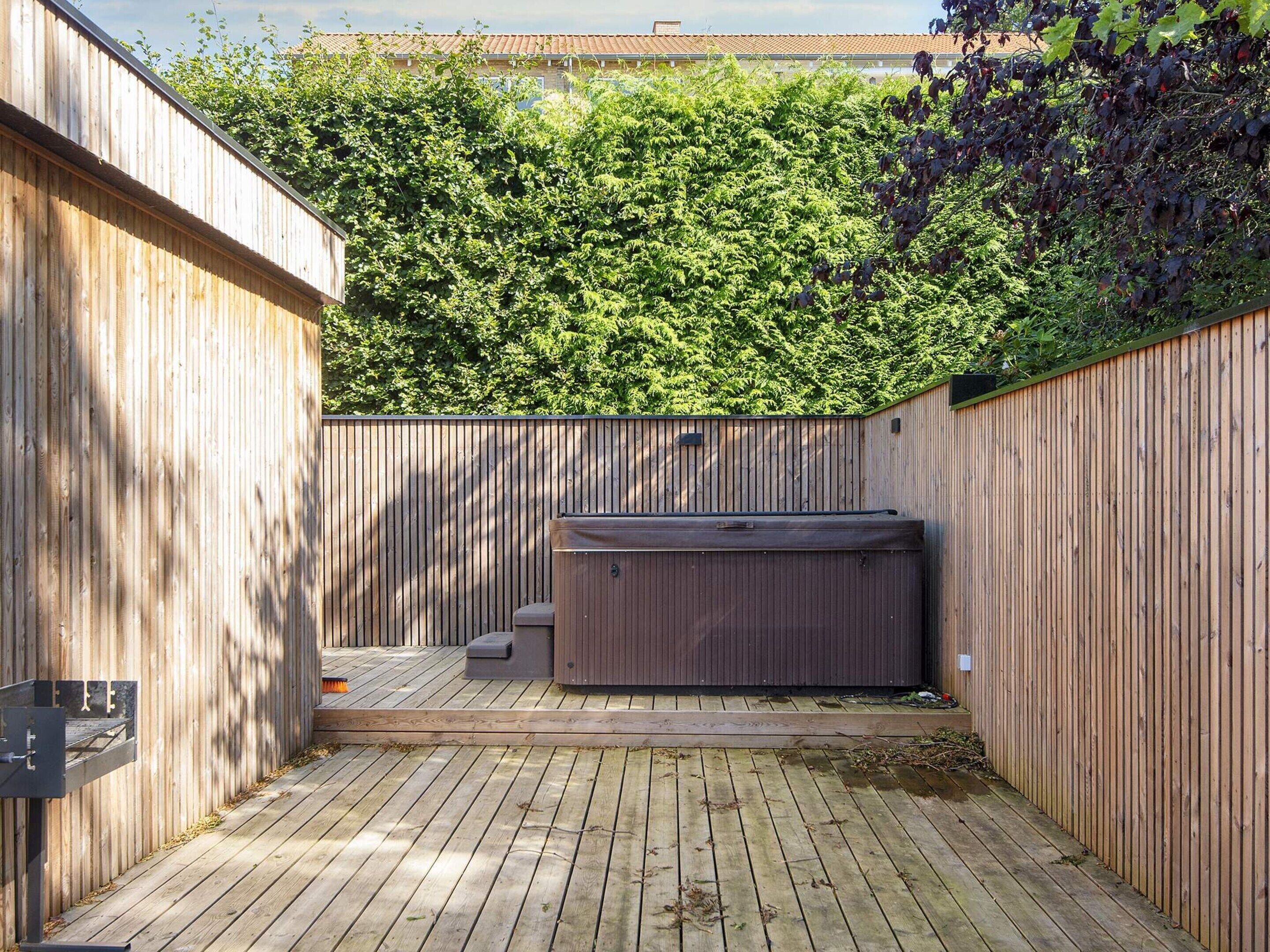 A wooden deck with a hot tub and a small seating area.