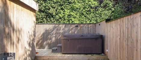 A wooden deck with a hot tub and a small seating area.