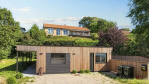 A modern building with a covered outdoor area, a paved entrance, and a wooden fence. - 4 Star Holiday Home in Ebeltoft (Ebeltoft)