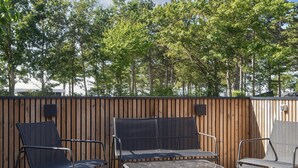 A wooden deck with outdoor furniture, including chairs and a table, surrounded by a wooden fence and trees. - 4 Star Holiday Home in Ebeltoft (Ebeltoft)