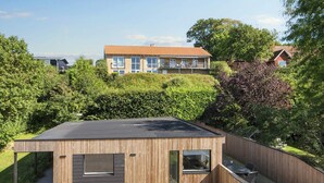 A modern wooden building with a flat roof, large windows, and a paved patio area. - 4 Star Holiday Home in Ebeltoft (Ebeltoft)