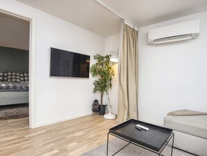 A modern living room with a flat-screen TV, a potted plant, a coffee table, and a sofa. - 4 Star Holiday Home in Ebeltoft (Ebeltoft)