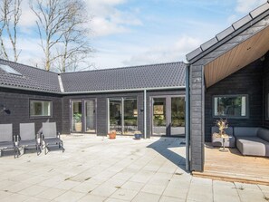 A modern house with a patio area, large windows, and outdoor seating. - 5 Star Holiday Home in Henne (Henne)