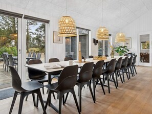 A spacious dining area with a long table, black chairs, and pendant lights. - 5 Star Holiday Home in Henne (Henne)