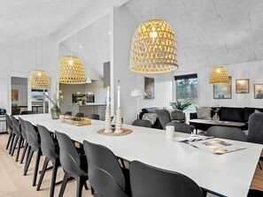 A modern dining area with a long table, black chairs, and decorative candle holders. - 5 Star Holiday Home in Henne (Henne)