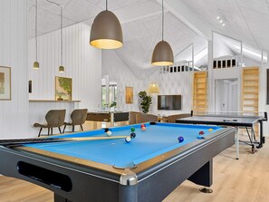 A pool table with balls, a seating area with chairs, a television, and pendant lighting. - 5 Star Holiday Home in Henne (Henne)