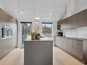 A modern kitchen with a central island, built-in appliances, and large windows. - 5 Star Holiday Home in Henne (Henne)
