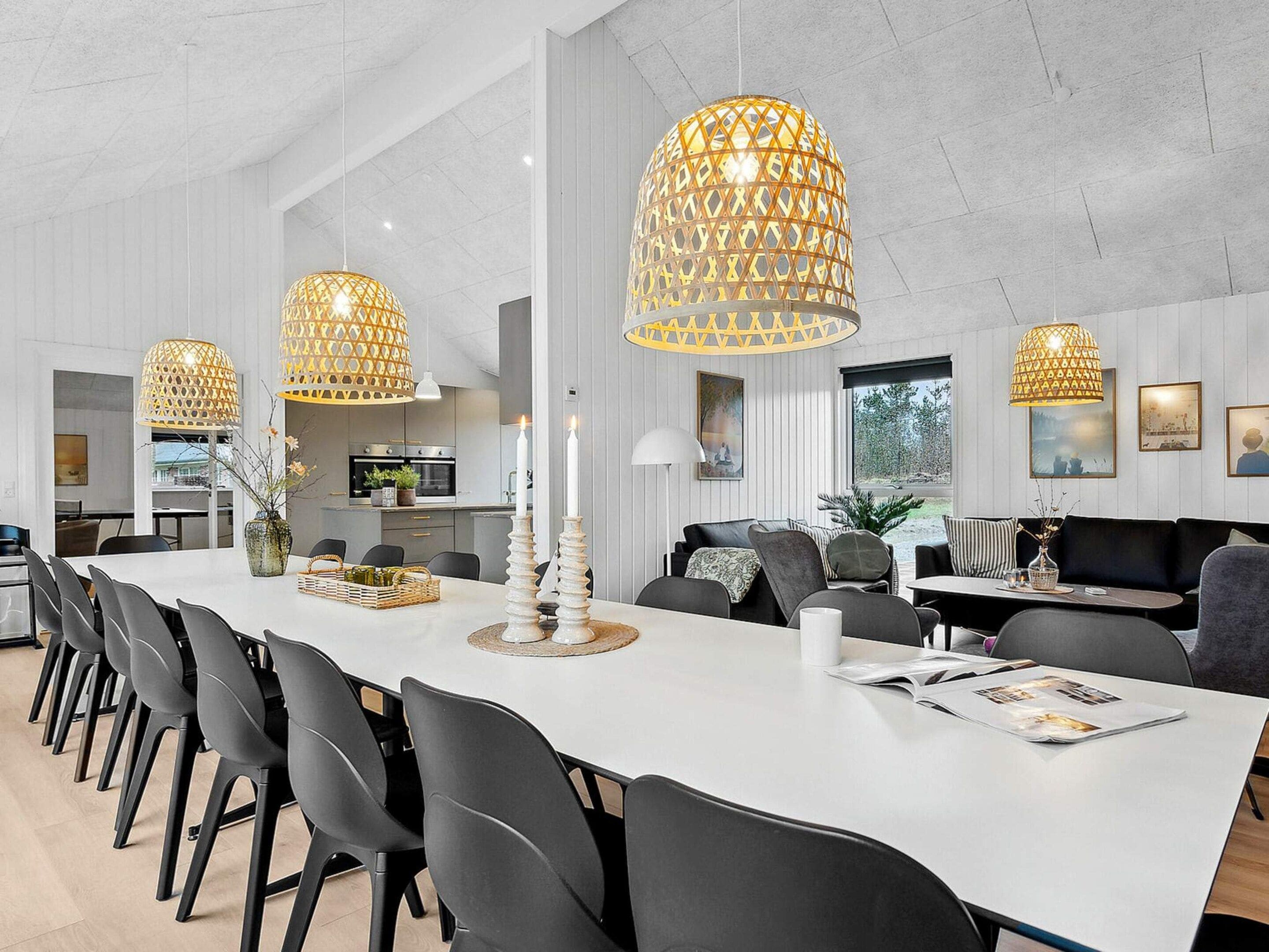 A modern dining area with a long table, black chairs, and decorative candle holders.
