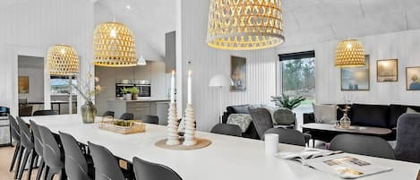 A modern dining area with a long table, black chairs, and decorative candle holders.