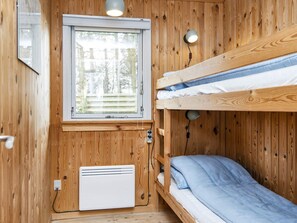 A compact room with a bunk bed, a window with blinds, a wall-mounted heater, and a small table with a lamp. - 6 Person Holiday Home in Struer (Struer)