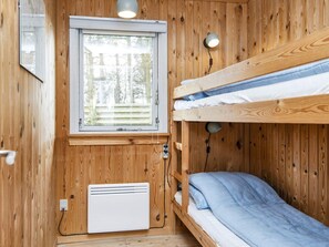 A small, wooden-paneled room with bunk beds, a window, a heater, and a wall-mounted lamp. - 6 Person Holiday Home in Struer (Struer)