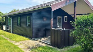 A single-story cabin with a dark exterior, a small porch, and a clear sky. - 6 Person Holiday Home in Struer (Struer)