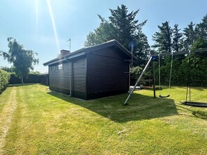 A black metal shed with a ladder, a swing set, and a well-maintained lawn. - 6 Person Holiday Home in Struer (Struer)