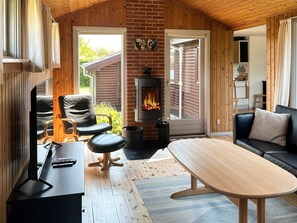 A cozy room with a fireplace, a sofa, a table, and a TV. - 6 Person Holiday Home in Struer (Struer)