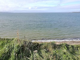 Paisaje costero con vista al mar y un primer plano de hierba.
