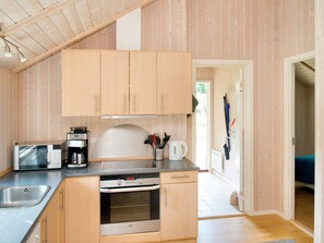 A compact kitchen with wooden cabinets, a microwave, a coffee maker, and a kettle.