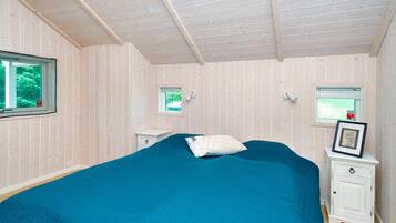 A bedroom with a large bed, two bedside tables, a window, and a small window.