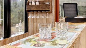 A bar area with a wooden wall, a neon 'BAR' sign, and a wooden shelf holding bottles and glasses. - 8 Person Holiday Home in Oksbol (Oksbol)