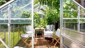 A greenhouse with a wooden deck, wicker furniture, and a glass enclosure. - 10 Person Holiday Home in Albaek (Aalbaek)