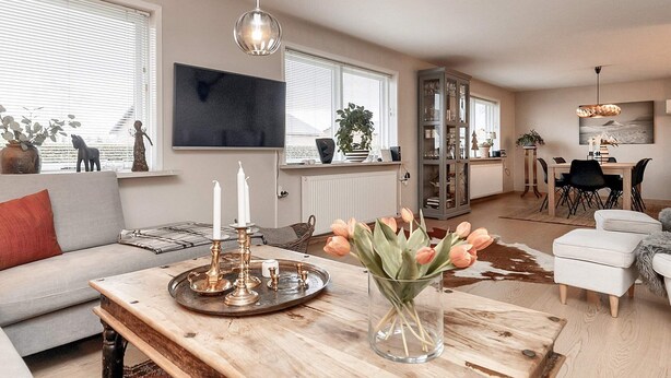 A modern living room with a sofa, coffee table, and a dining area with chairs and a table. - 10 Person Holiday Home in Albaek (Aalbaek)