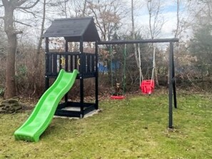 A playground with a green slide and swings. - 8 Person Holiday Home in Skjern (Skjern)