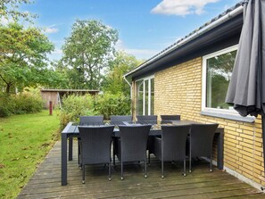 A patio with a table and chairs, a brick wall, and a window. - 8 Person Holiday Home in Skjern (Skjern)