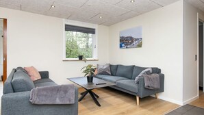 A modern living room with two grey sofas, a coffee table, and a window with a view of trees. - 8 Person Holiday Home in Skjern (Skjern)