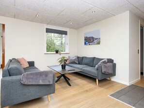 A modern living room with two grey sofas, a coffee table, and a window with a view of trees. - 8 Person Holiday Home in Skjern (Skjern)