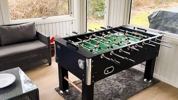 A foosball table in a room with a sofa and a table with a paper plate.