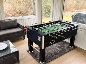 A foosball table in a room with a sofa and a table with a paper plate. - 8 Person Holiday Home in Skjern (Skjern)