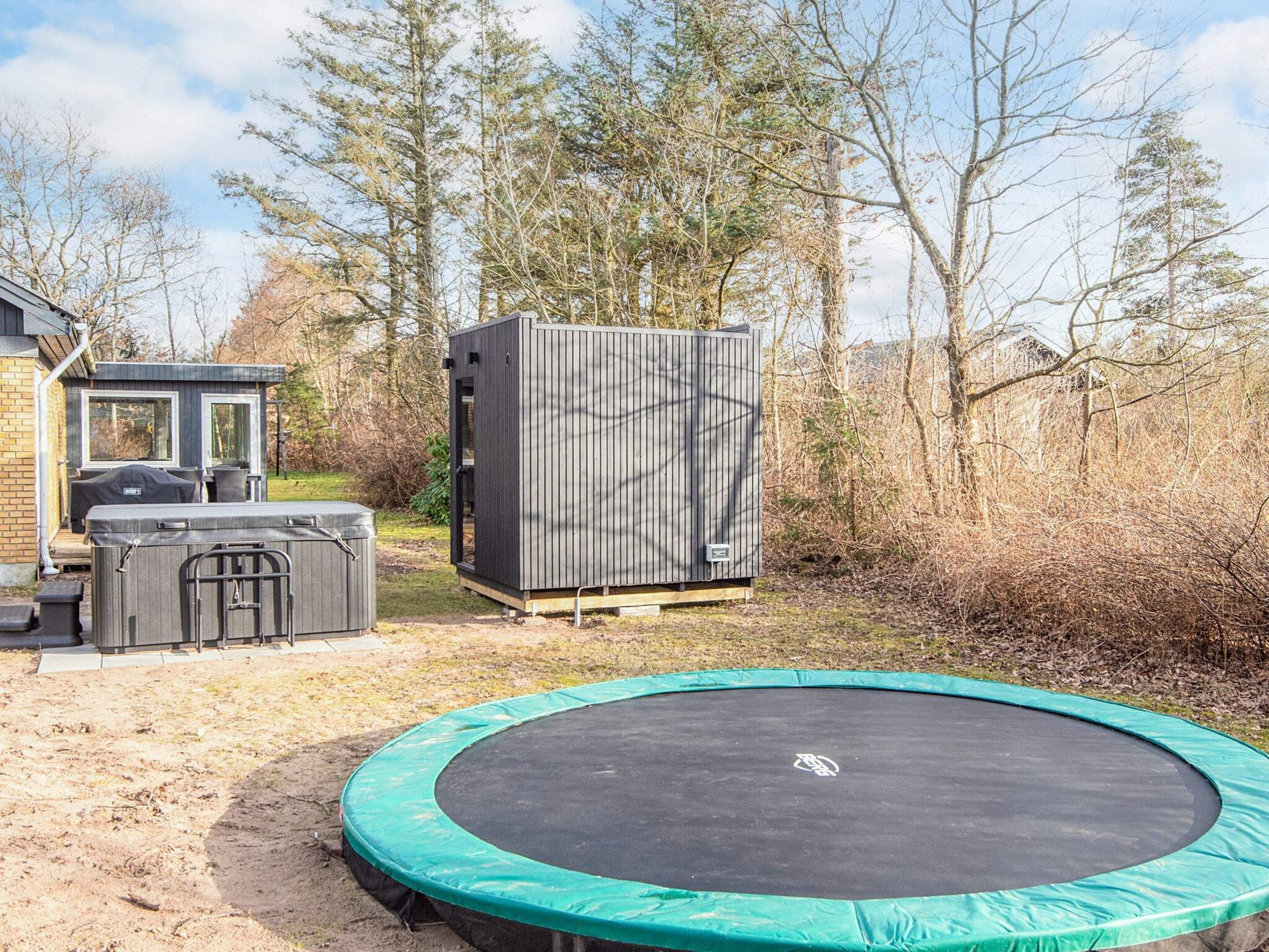 A backyard with a trampoline, a grill, and a storage shed.