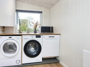 A compact kitchen with a washing machine, a microwave, and a window above the sink. - 8 Person Holiday Home in Skjern (Skjern)