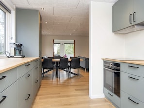 A modern kitchen with grey cabinets, a built-in oven, and a coffee machine. - 8 Person Holiday Home in Skjern (Skjern)