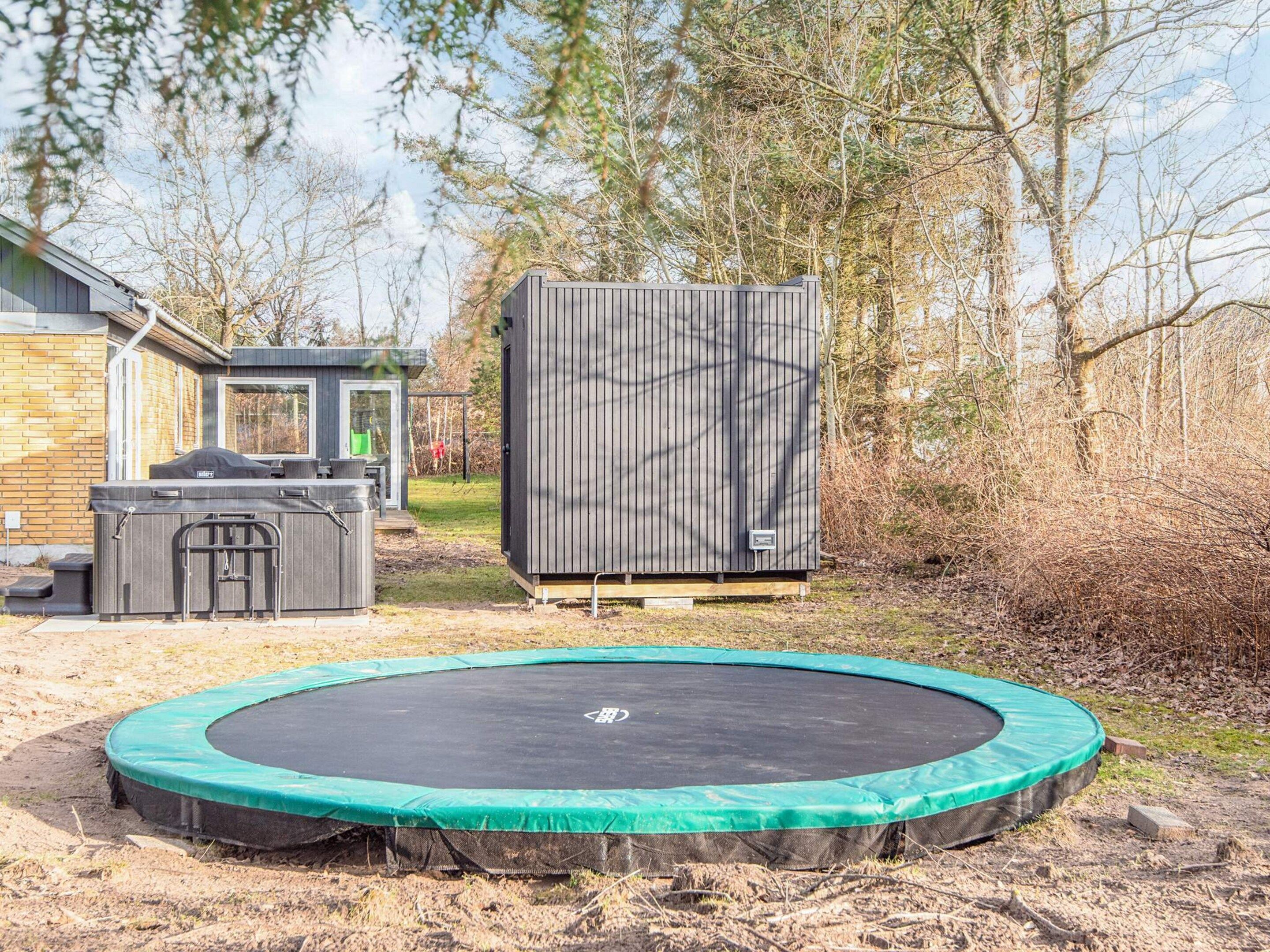 A backyard with a trampoline, a hot tub, and a shed.